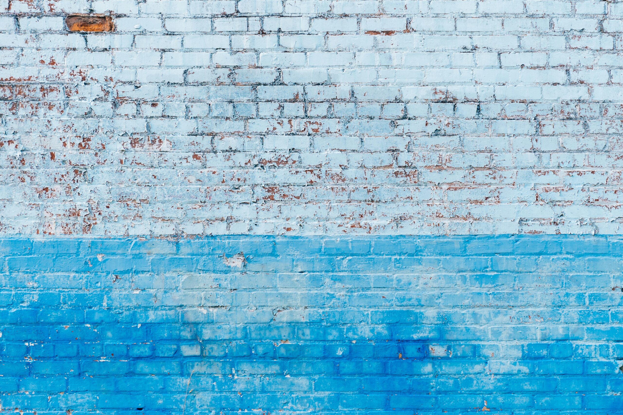 A textured brick wall with a two-tone blue and white painted surface.